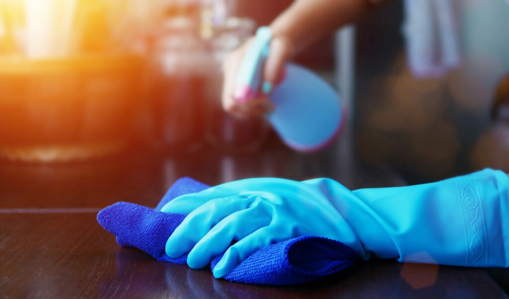 Person in blue gloves cleaning a surface with a spray bottle and cloth during a move out cleaning in the Bay Area.